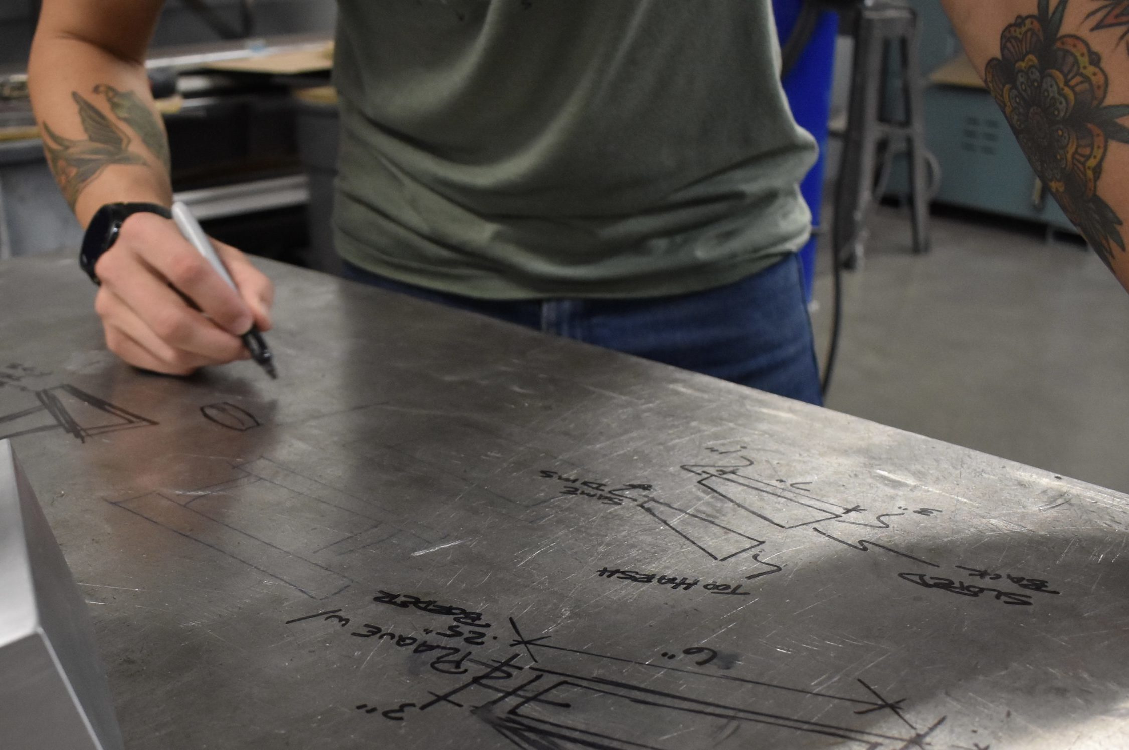 A member of the JKS Incorporated Creative Services team sketching a display diagram on a steel table.