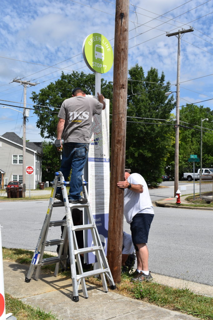 Our installation crew works on a bus stop sign for the High Point Market.